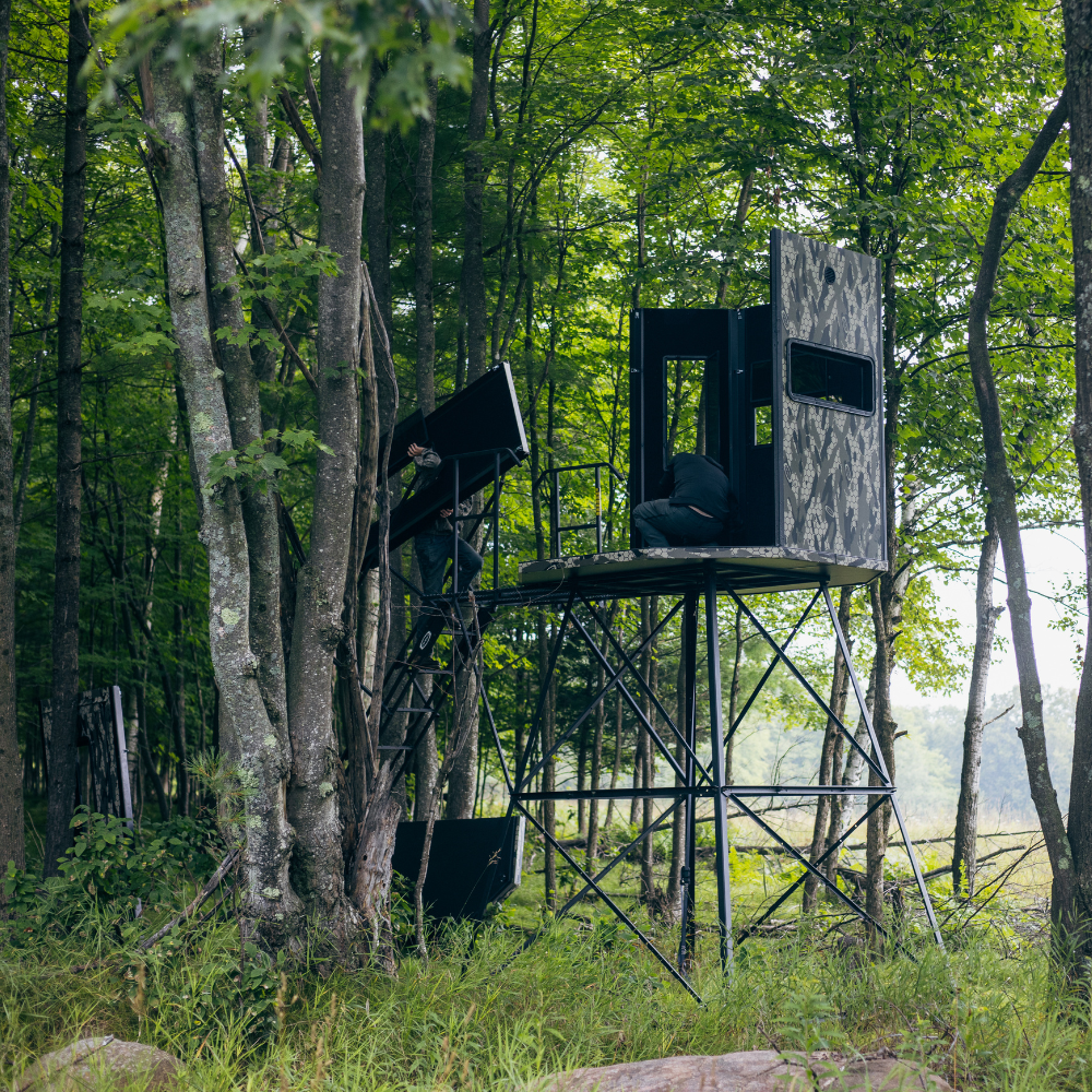two people assembling an Orion 78T modular deer blind in the forest 