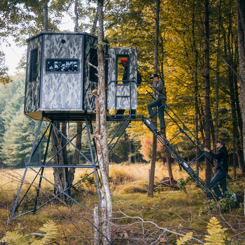 three people climbing stairs into an Orion 78T modular deer blind on an autumn morning in a forest